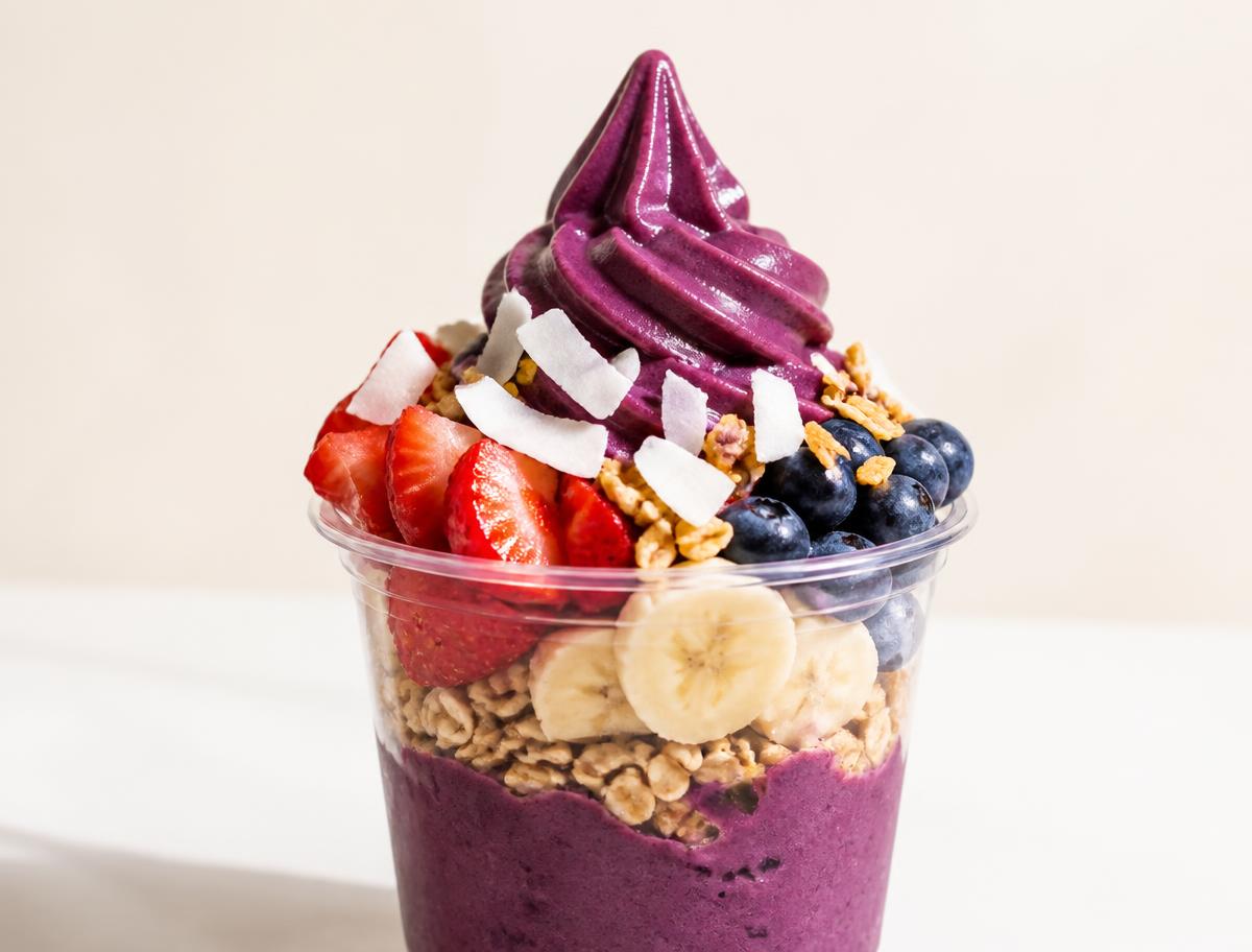 Açaí soft-serve cup topped with berries, banana, granola and coconut